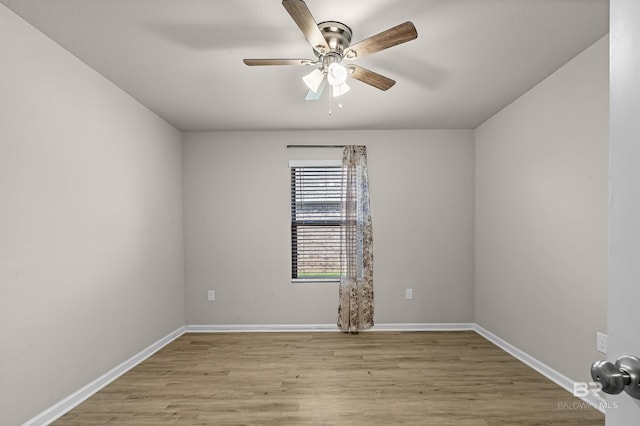 spare room featuring a ceiling fan, baseboards, and light wood finished floors