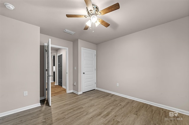 unfurnished bedroom with a ceiling fan, wood finished floors, visible vents, and baseboards