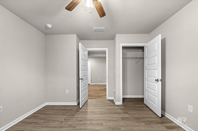 unfurnished bedroom with visible vents, ceiling fan, baseboards, wood finished floors, and a closet