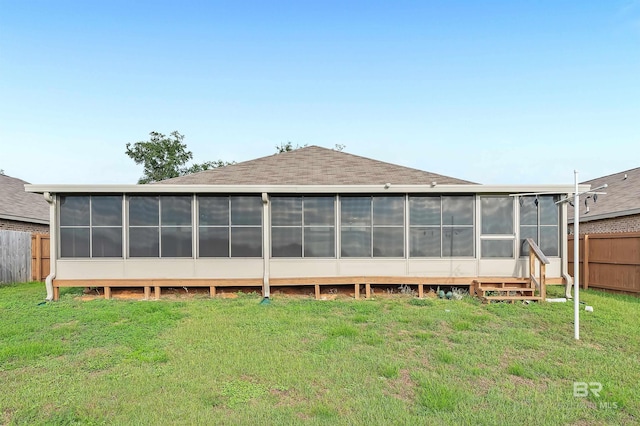 back of property featuring fence, a lawn, and a sunroom