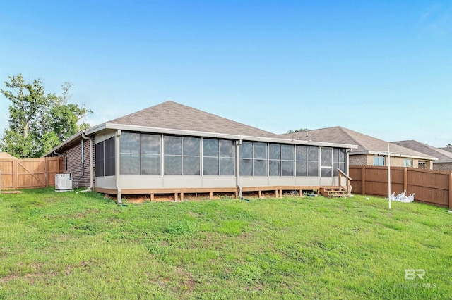 back of house featuring fence private yard, a yard, and a sunroom