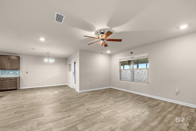 unfurnished living room with visible vents, baseboards, light wood-style flooring, and ceiling fan with notable chandelier