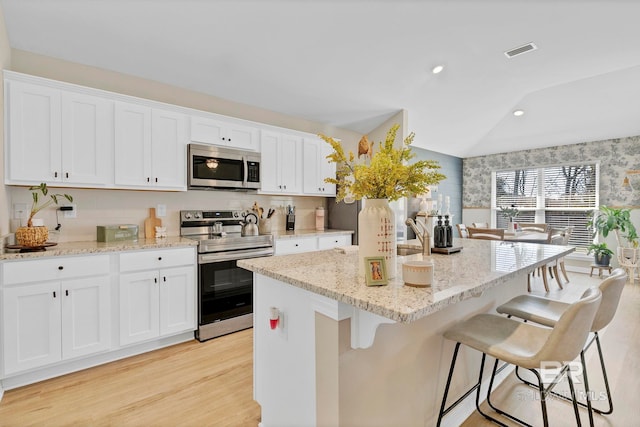1203 Hayward Loop, Foley, AL 36535 - kitchen featuring lofted ceiling, visible vents, stainless steel appliances, and a kitchen breakfast bar