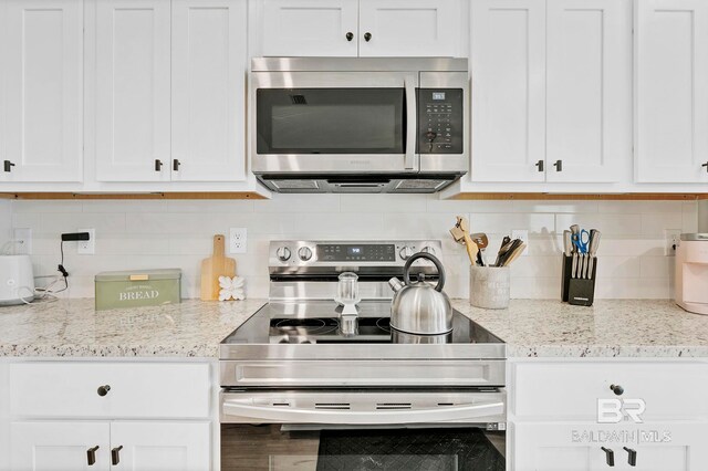 1203 Hayward Loop, Foley, AL 36535 - kitchen with light stone countertops, appliances with stainless steel finishes, white cabinets, and backsplash