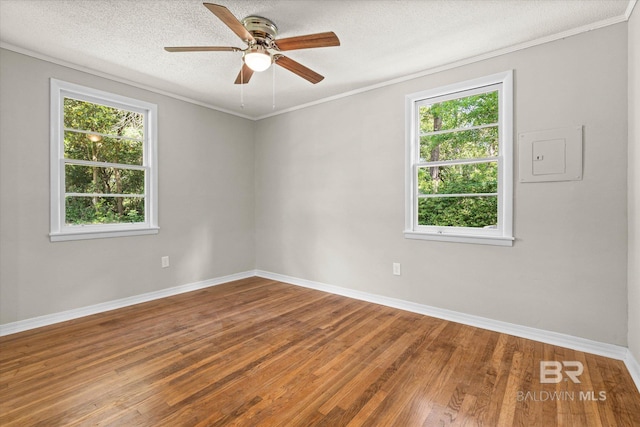 unfurnished room featuring wood finished floors, a healthy amount of sunlight, a ceiling fan, and ornamental molding
