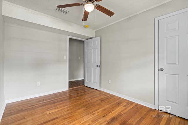 unfurnished bedroom with light wood-type flooring, baseboards, visible vents, ceiling fan, and ornamental molding