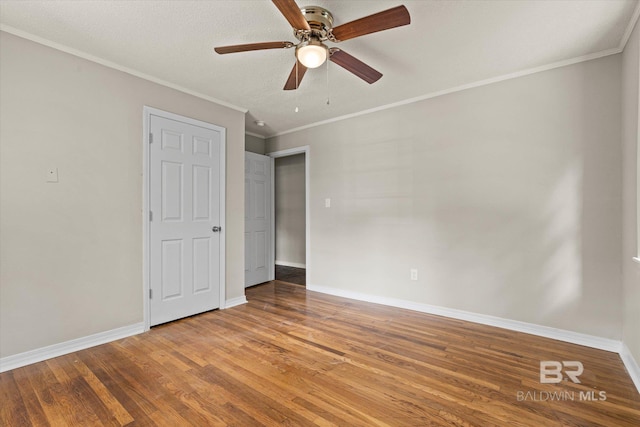 unfurnished bedroom featuring baseboards, wood finished floors, and crown molding
