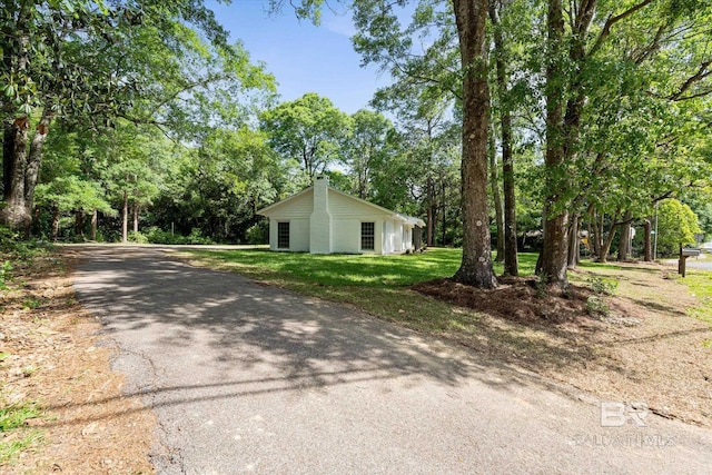 exterior space with a chimney, aphalt driveway, and a yard