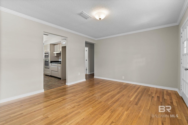 spare room featuring light wood finished floors, visible vents, a textured ceiling, and crown molding