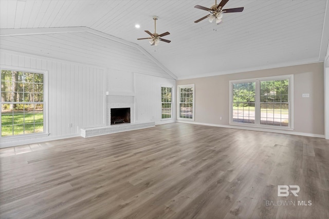 unfurnished living room with vaulted ceiling, baseboards, a ceiling fan, wood finished floors, and a brick fireplace