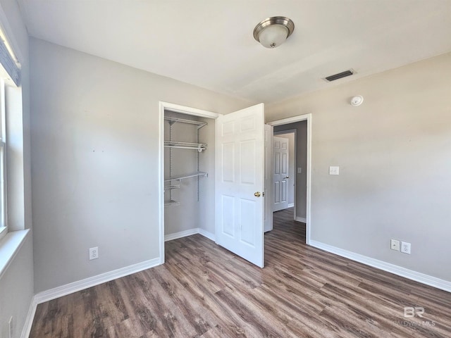 unfurnished bedroom with dark hardwood / wood-style flooring and a closet