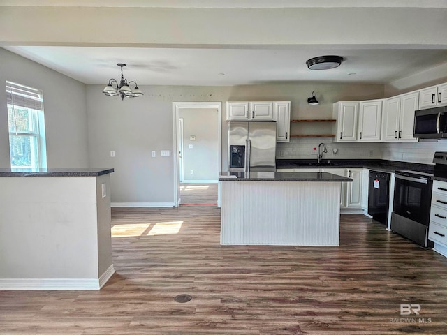 kitchen with pendant lighting, hardwood / wood-style flooring, appliances with stainless steel finishes, white cabinets, and a kitchen island