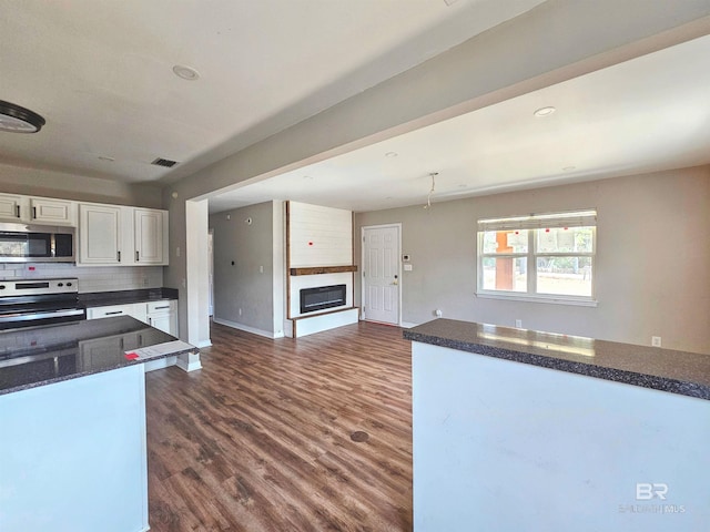 kitchen with white cabinetry, backsplash, dark wood-type flooring, and stainless steel appliances