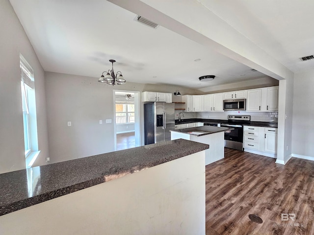 kitchen featuring appliances with stainless steel finishes, dark hardwood / wood-style flooring, hanging light fixtures, and white cabinets