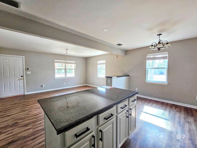 kitchen featuring white cabinetry, dark hardwood / wood-style floors, a center island, beamed ceiling, and a chandelier