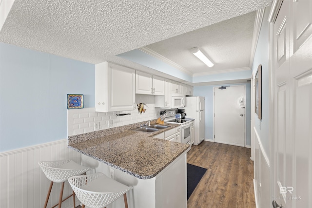 kitchen with white appliances, kitchen peninsula, dark stone counters, a textured ceiling, and white cabinetry