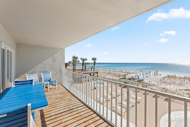 balcony featuring a view of the beach and a water view