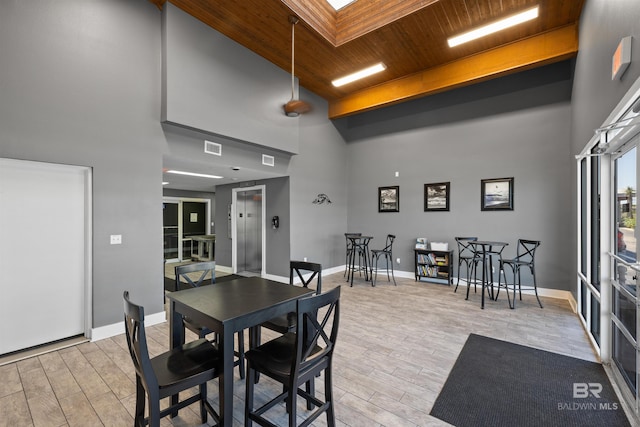 dining area featuring a high ceiling, a skylight, elevator, and wooden ceiling