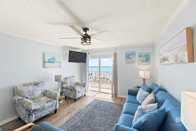 living room with light wood-type flooring, ornamental molding, a textured ceiling, and ceiling fan