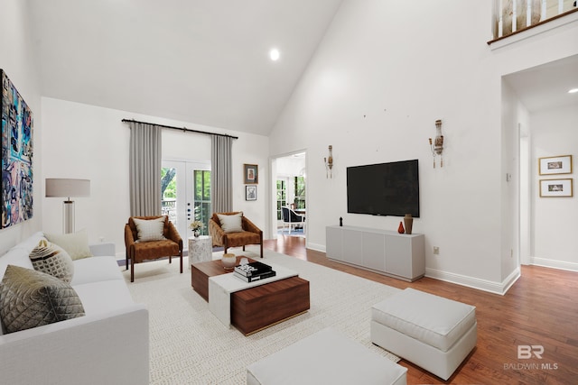 living area with recessed lighting, high vaulted ceiling, wood finished floors, baseboards, and french doors