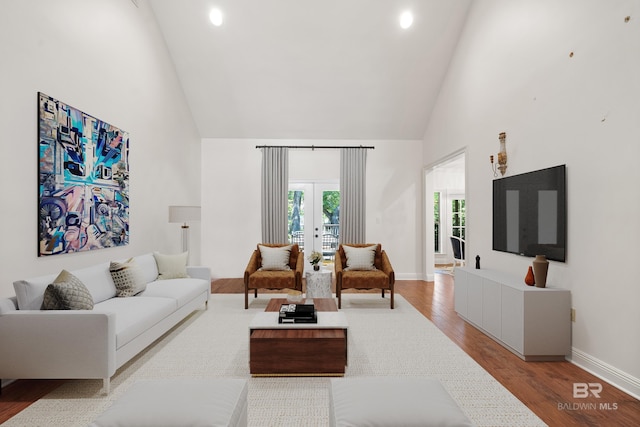 living area featuring wood finished floors, french doors, high vaulted ceiling, and baseboards