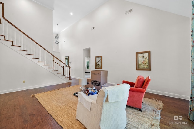 living area featuring stairway, high vaulted ceiling, visible vents, baseboards, and wood finished floors