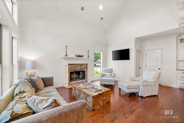 living area with a fireplace with flush hearth, dark wood-type flooring, high vaulted ceiling, and baseboards
