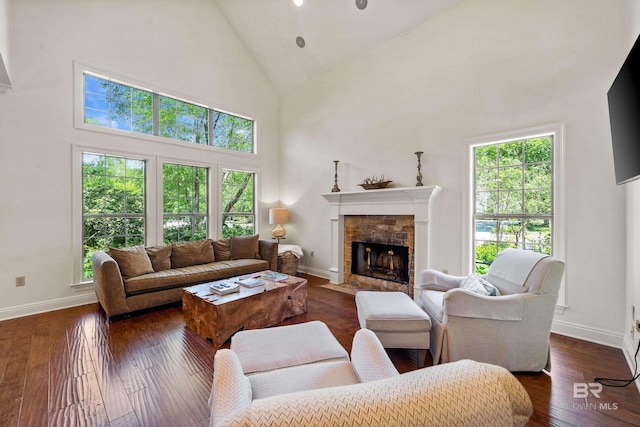 living room featuring a fireplace with flush hearth, a wealth of natural light, high vaulted ceiling, and baseboards