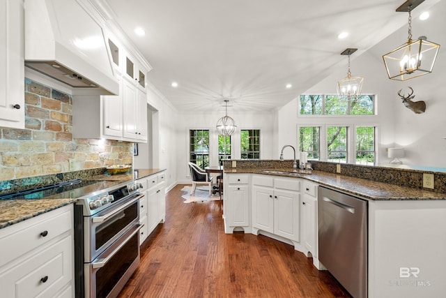 kitchen featuring tasteful backsplash, custom range hood, a sink, a chandelier, and stainless steel appliances