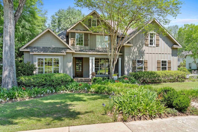 craftsman-style house with roof with shingles, board and batten siding, and a front lawn