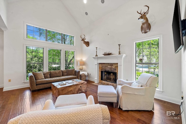 living area featuring baseboards, high vaulted ceiling, hardwood / wood-style flooring, and a tile fireplace