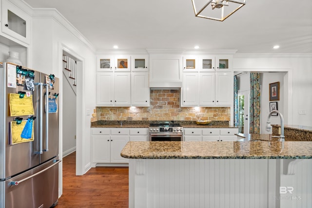 kitchen featuring dark stone counters, white cabinets, a sink, appliances with stainless steel finishes, and dark wood finished floors