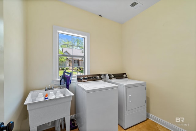 washroom with a sink, visible vents, baseboards, separate washer and dryer, and laundry area