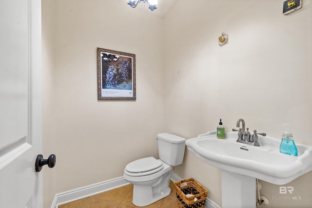 half bath featuring tile patterned floors, a sink, toilet, and baseboards