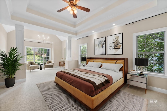 bedroom featuring multiple windows, a raised ceiling, light carpet, and decorative columns
