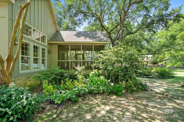 back of house featuring board and batten siding, a sunroom, and roof with shingles