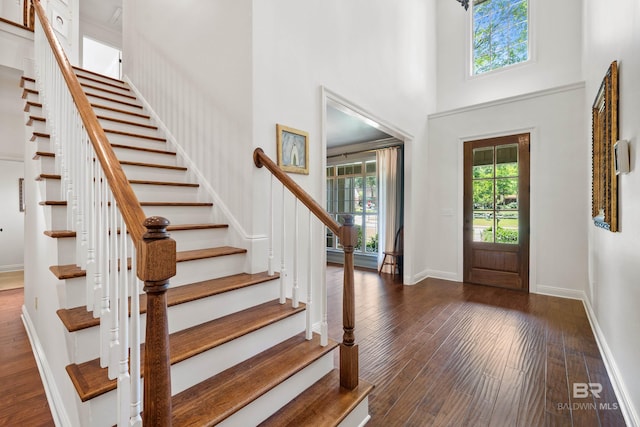 foyer entrance with baseboards, stairs, dark wood-style flooring, and a high ceiling
