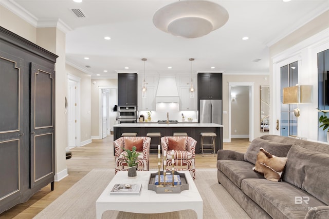 living room featuring light hardwood / wood-style flooring, crown molding, and sink