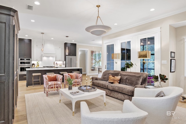 living room with light wood-type flooring and ornamental molding