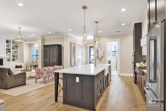 kitchen featuring sink, light hardwood / wood-style flooring, an island with sink, pendant lighting, and high quality fridge