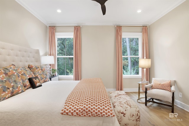 bedroom featuring ceiling fan, ornamental molding, multiple windows, and light hardwood / wood-style flooring