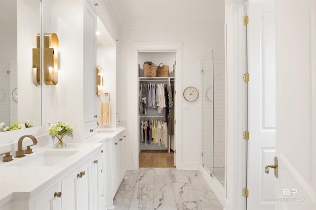 bathroom featuring vanity, a shower with shower door, and crown molding