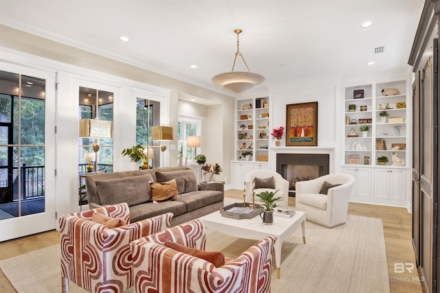 interior space featuring built in shelves, light hardwood / wood-style floors, and ornamental molding