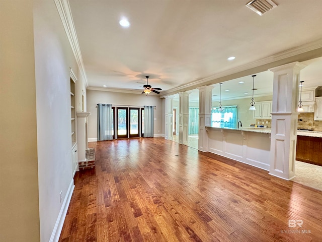 unfurnished living room featuring hardwood / wood-style floors, crown molding, and ceiling fan