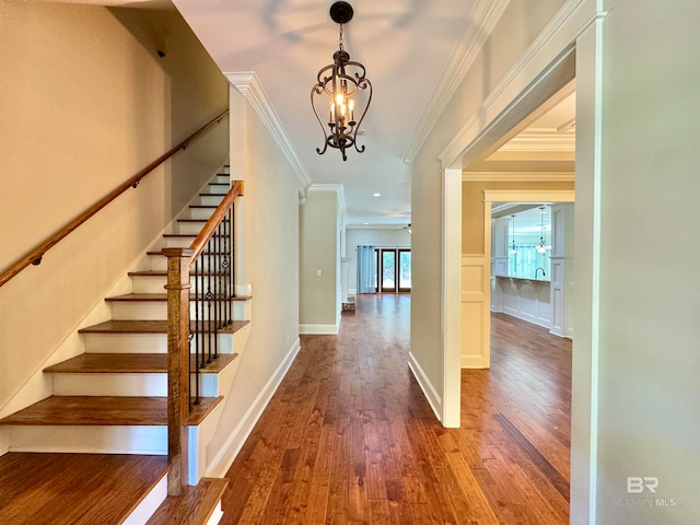 stairway featuring crown molding, wood-type flooring, and ceiling fan with notable chandelier