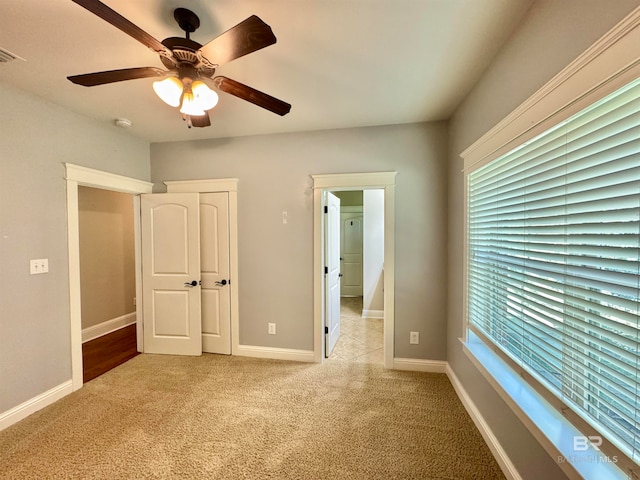 unfurnished bedroom with ceiling fan and light colored carpet