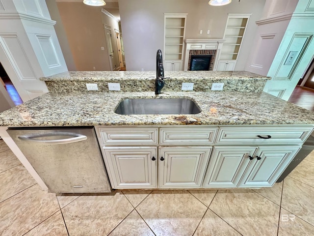 kitchen featuring sink, an island with sink, light stone counters, and dishwasher