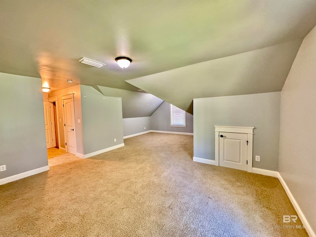 additional living space with light colored carpet and vaulted ceiling