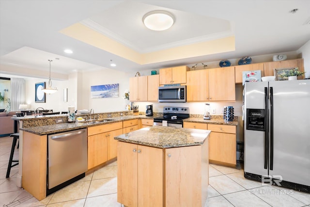 kitchen with a tray ceiling, appliances with stainless steel finishes, a peninsula, and light brown cabinets