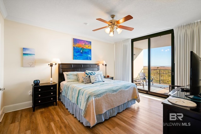 bedroom with baseboards, a ceiling fan, wood finished floors, access to exterior, and expansive windows